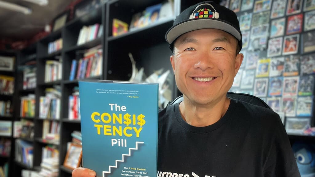 Consistency Pill book held up by author, Simon Chan